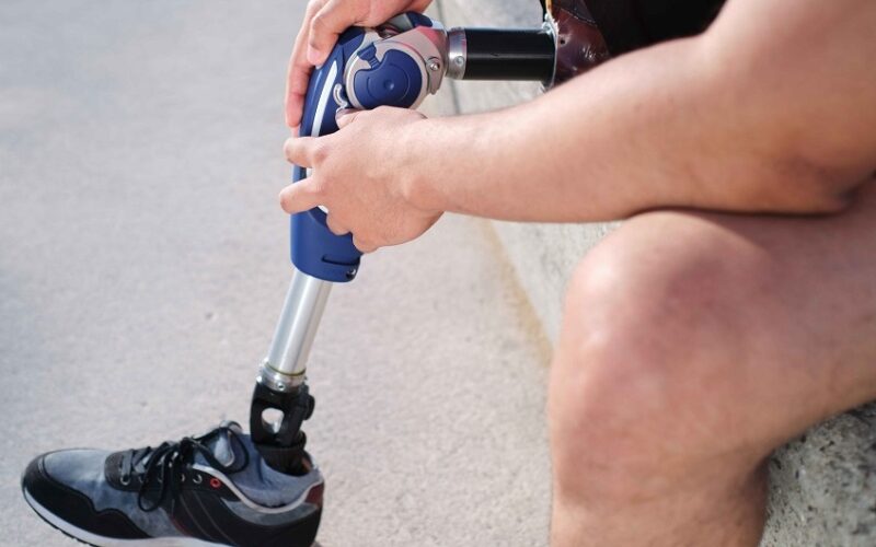 Midsection of a young man adjusting his prosthetic leg outdoor.